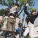 Two teenagers joyfully jumping outdoors in Šiluva, Lithuania under a bright blue sky. Captured in springtime.