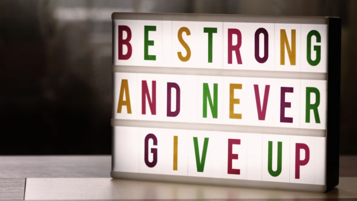 Inspirational lightbox displaying the motivational quote 'Be Strong and Never Give Up' indoors.