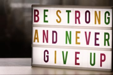 Inspirational lightbox displaying the motivational quote 'Be Strong and Never Give Up' indoors.