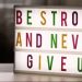 Inspirational lightbox displaying the motivational quote 'Be Strong and Never Give Up' indoors.